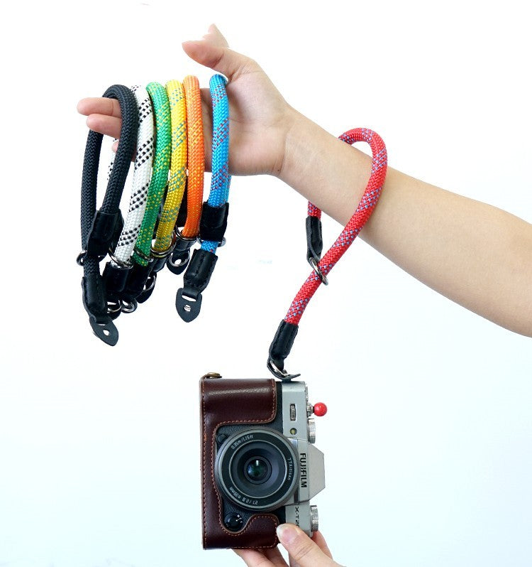Colorful camera wrist straps (black, green, orange, blue, red) being held with a camera in hand for secure carrying.