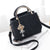 Stylish black shoulder bag with gold handle and decorative charm, perfect for women's fashion and daily use.